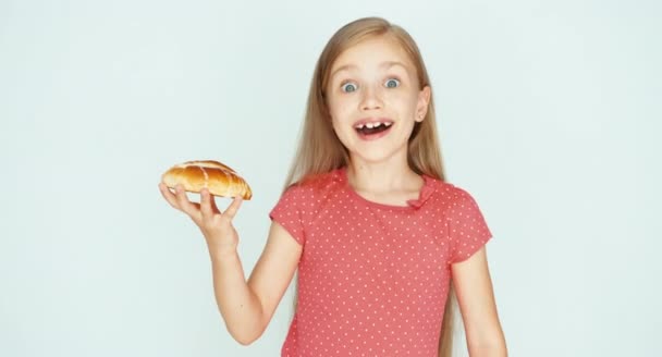 Meisje houdt een cake met kaas en tonen op de camera. Kind op de witte achtergrond. Duim omhoog. OK — Stockvideo