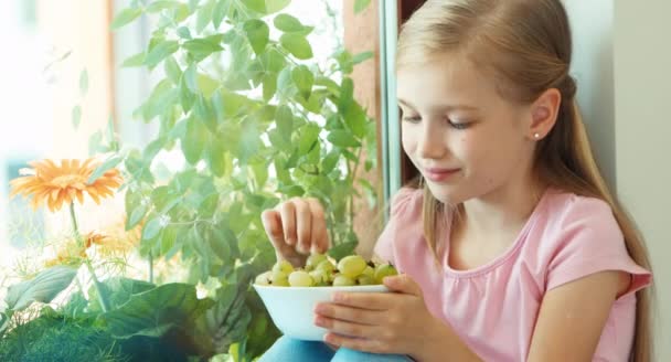 Closeup portrait girl eating gooseberries and and offers berries at camera — Stock Video