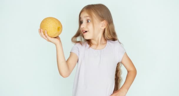 Mädchen spielt mit einer kleinen süßen Melone und zeigt sie vor der Kamera auf dem weißen Hintergrund. Daumen hoch. ok — Stockvideo