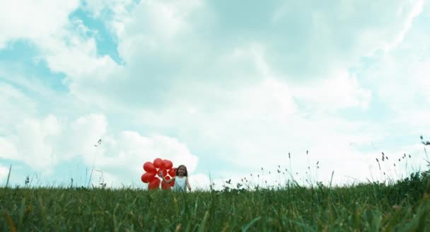 Girl with red balloons walking at camera — ストック動画