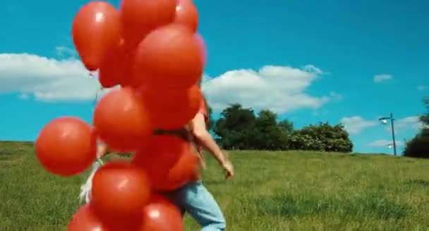 Portrait girl with red balloons walking in the meadow — Stock Video