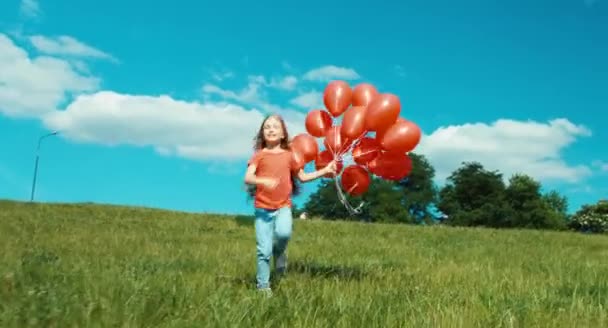 Meisje met rode ballonnen wandelen vanaf de heuvel — Stockvideo