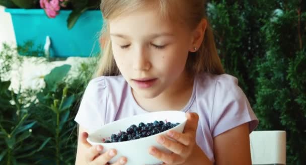 Dívka, funění a ukazující mísa s borůvkami na kameru. Closeup — Stock video