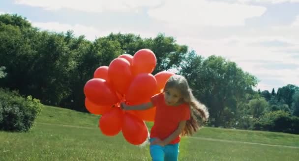 Girl with red balloons walking in the hill and smiling — Stockvideo