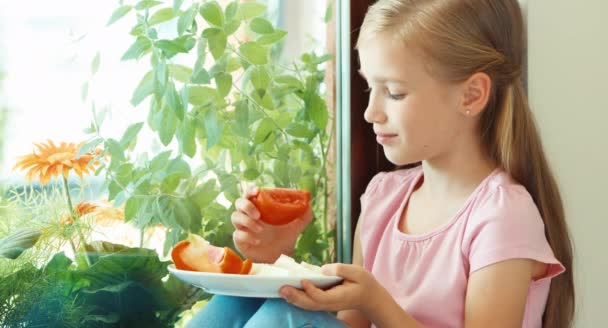 Portrait girl sniffing tomato against window and smiling — Stock video