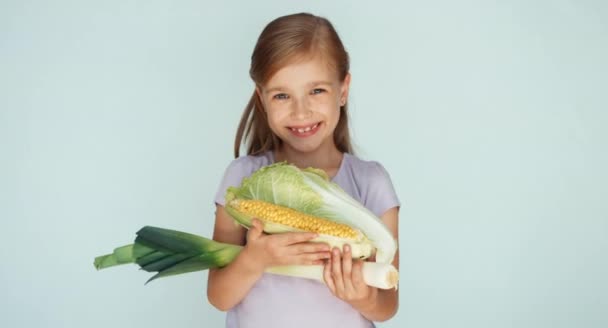 Girl holding vegetables cabbage, corn, celery and smiling at camera — Stockvideo