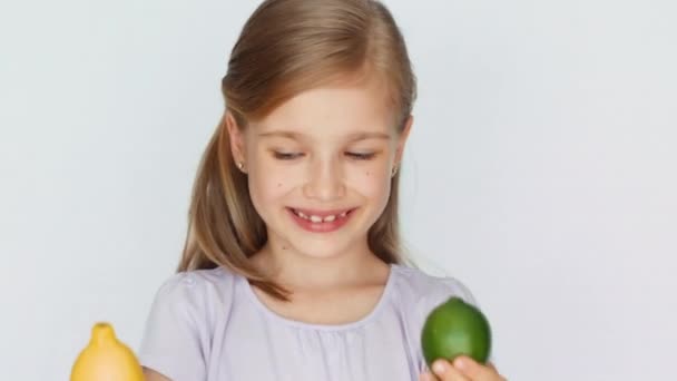 Девушка рассматривает лимон и лайм и смеется над камерой — стоковое видео