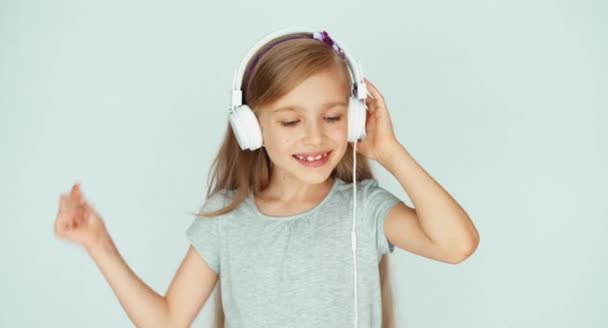 Chica escuchando música y bailando sobre un fondo blanco — Vídeo de stock