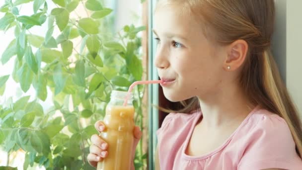 Girl drinking juice against window and smiling at camera. Zooming — Stockvideo