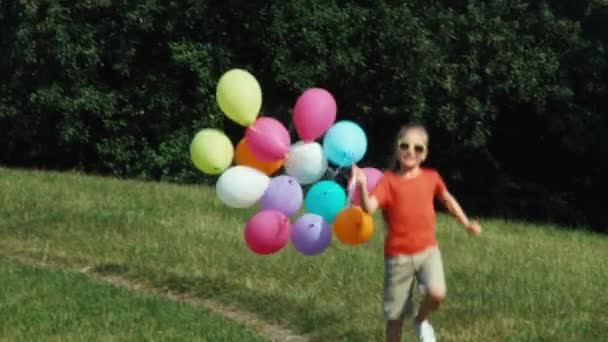 Chica alegre corriendo con globos en el parque — Vídeos de Stock