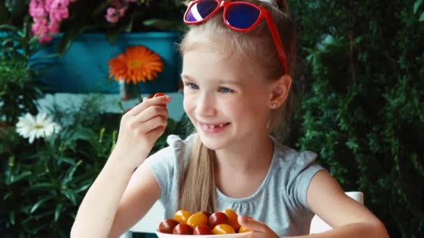 Meisje eten cherry tomaat en glimlachend in de camera. Duim omhoog. OK. Zoomen — Stockvideo