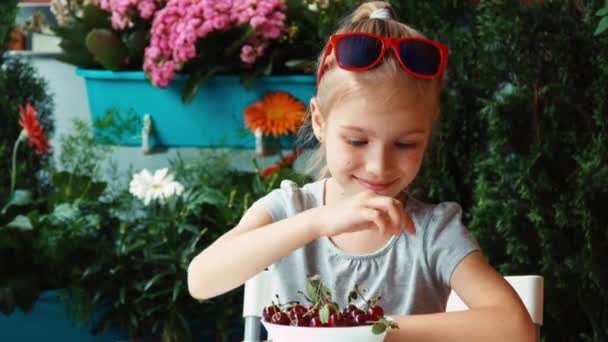 Girl eating a cherry. Big eyes. Child eating berries and admires and looking at camera. Thumb up. Ok. Zooming — Stock Video