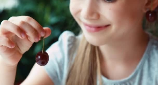 Extrema close up retrato menina comendo uma cereja e sorrindo para a câmera — Vídeo de Stock