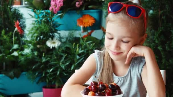 Portret meisje kersen eten en afstand uitkijken. Zoomen — Stockvideo