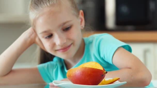 Extreme closeup portrait girl looking at mango and camera. Child promotes fruit mango — Stock Video