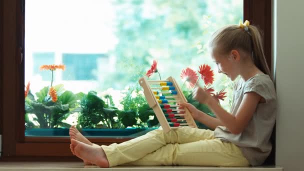 Girl learning to count with abacus and sitting on the sill. Thumbs up. Ok. Zooming — Stock Video