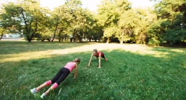 Atleta familia madre e hija haciendo ejercicio en el parque. Cámara volando alrededor de 1 — Vídeo de stock