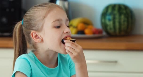 Ritratto ragazza mangiare prugne. Bambino promuove prugne di frutta e sorridente alla macchina fotografica — Video Stock