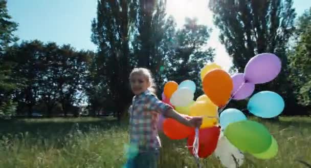 Stående flicka kör med ballonger i parken — Stockvideo