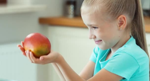 Kind hat Spaß mit Früchten. Kind schnüffelt Mango und fördert Mango vor der Kamera — Stockvideo