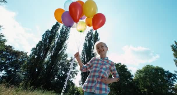 Girl playing with balloons. Child with balloons against the sun — Stock Video