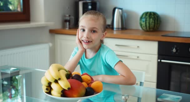 La fille annonce des fruits. Enfant regardant la caméra et souriant — Video