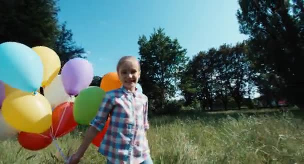 Meisje kind spinnen met ballonnen tegen de hemel in het zonlicht — Stockvideo
