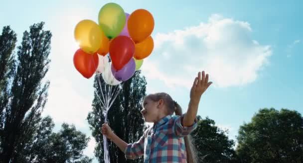 Niño sosteniendo un montón de globos y estirándose en el cielo — Vídeos de Stock