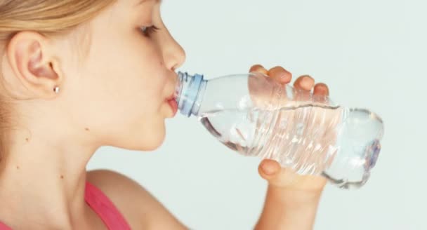 Extreme close-up portret schattig meisje drinkwater uit de fles op camera — Stockvideo