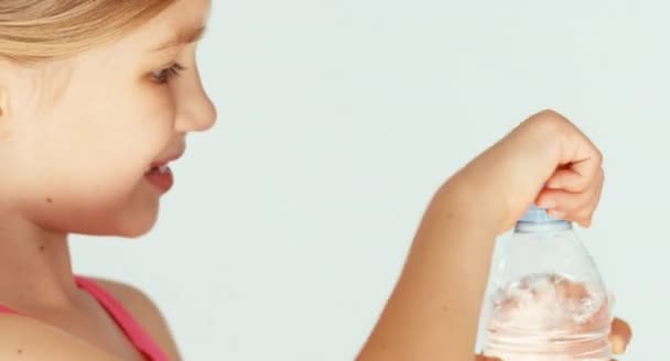 Екстремальний крупним планом портрет милої дівчини-дитини, що п'є воду з пляшки на камеру — стокове відео