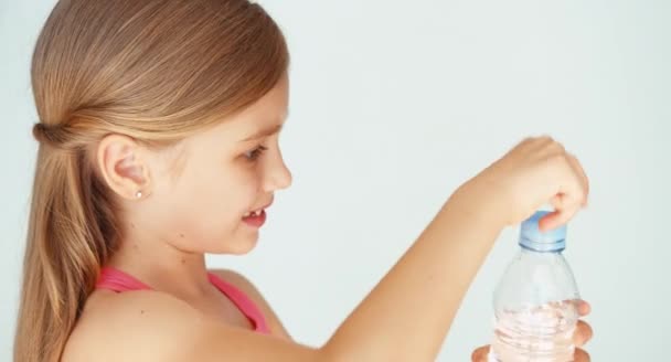 Primo piano ritratto sportivo ragazza bambino aprendo bottiglia d'acqua e acqua potabile a macchina fotografica — Video Stock