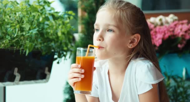 Nahaufnahme Porträt Mädchen, das Saft gegen die Blume trinkt und in die Kamera lächelt — Stockvideo