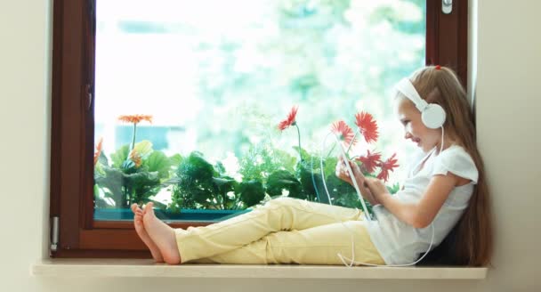 Porträt Mädchen mit Tablet-PC gegen die Blume. Mädchen hört Musik über Kopfhörer. Hand ja. ok — Stockvideo
