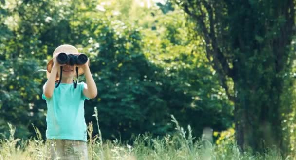 Mädchen blickt durch Ferngläser in Kamera und winkt und lacht — Stockvideo