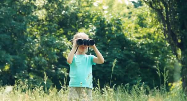 Mädchen blickt durch Fernglas in Kamera und winkt — Stockvideo