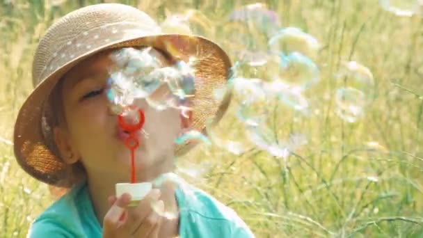 Closeup portrait girl blowing soap bubbles in the grass — Stock Video