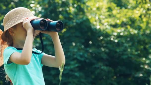 Detailní portrét dívka dívá dalekohledem na fotoaparát a mává rukou a směje se — Stock video