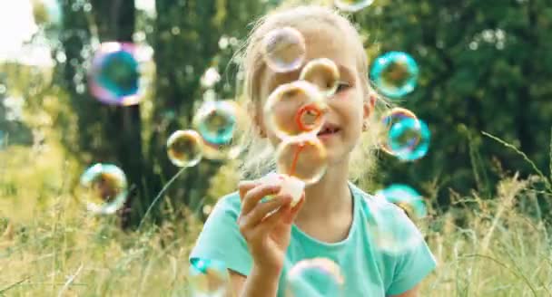 Vértes portré lány buborékokat eregetett szappan, a fűben — Stock videók