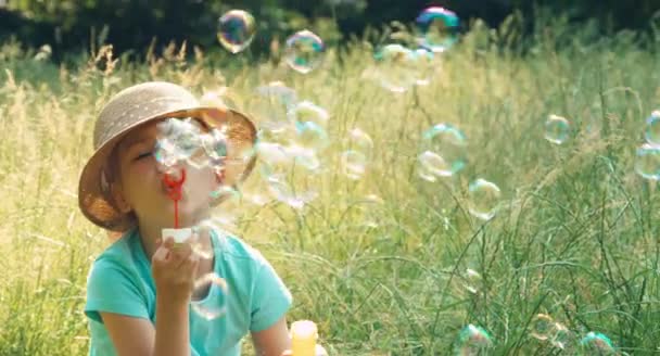 Дівчина дме мильні бульбашки в траві — стокове відео