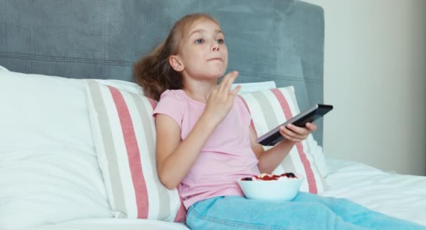 Menina assiste TV e comer doces — Vídeo de Stock