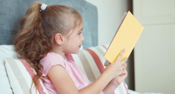 Mädchen liest ein Buch und umarmt es und lächelt — Stockvideo