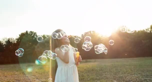 Flicka som blåser såpbubblor i solljus. Bländning — Stockvideo
