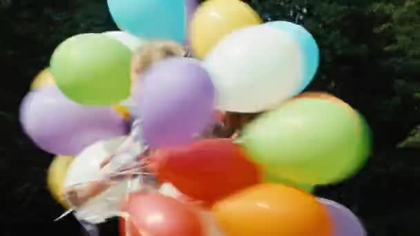 Closeup portrait girl jumping with balloons and spinning and laughing at camera — Stock Video