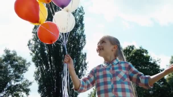 Closeup portret meisje met ballonnen met lens flare. Kind met ballonnen tegen de hemel en zon — Stockvideo