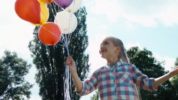 Vértes portré lány, lencse fényfolt léggömbök. Gyermek a léggömbök az ég és a nap ellen — Stock videók