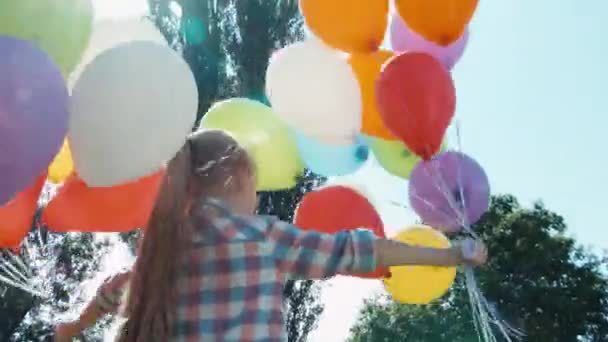 Closeup menina retrato girando com balões e olhando para a câmera contra o sol. Inflação da lente — Vídeo de Stock