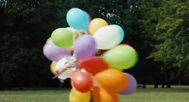 Chica saltando con globos y girando y riendo de la cámara — Vídeos de Stock