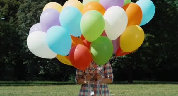 Flickan tittar ut bakom ballonger och hoppar och skrattar — Stockvideo