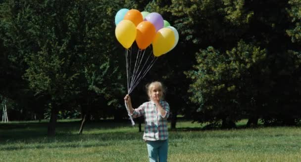 Девушка держит воздушные шары в парке — стоковое видео
