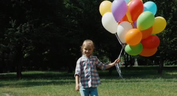 Flicka promenader och spinning med ballonger på ängen på kamera — Stockvideo